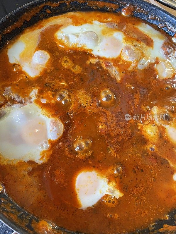 地中海健康早餐shakshouka / shakshuka / chakchouka在平底锅里，鸡蛋煮在西红柿、辣椒、洋葱、橄榄油和大蒜的酱汁里